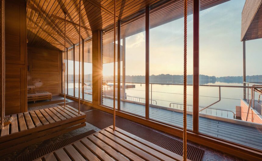 Blick von hängenden Holzliegen durch eine große Fensterfront auf den Ruppiner See hinaus.