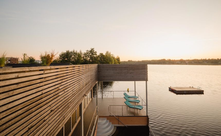 Außenansicht von der Dachterrasse der See Sauna mit Blick auf ein hölzernes Floß auf dem See